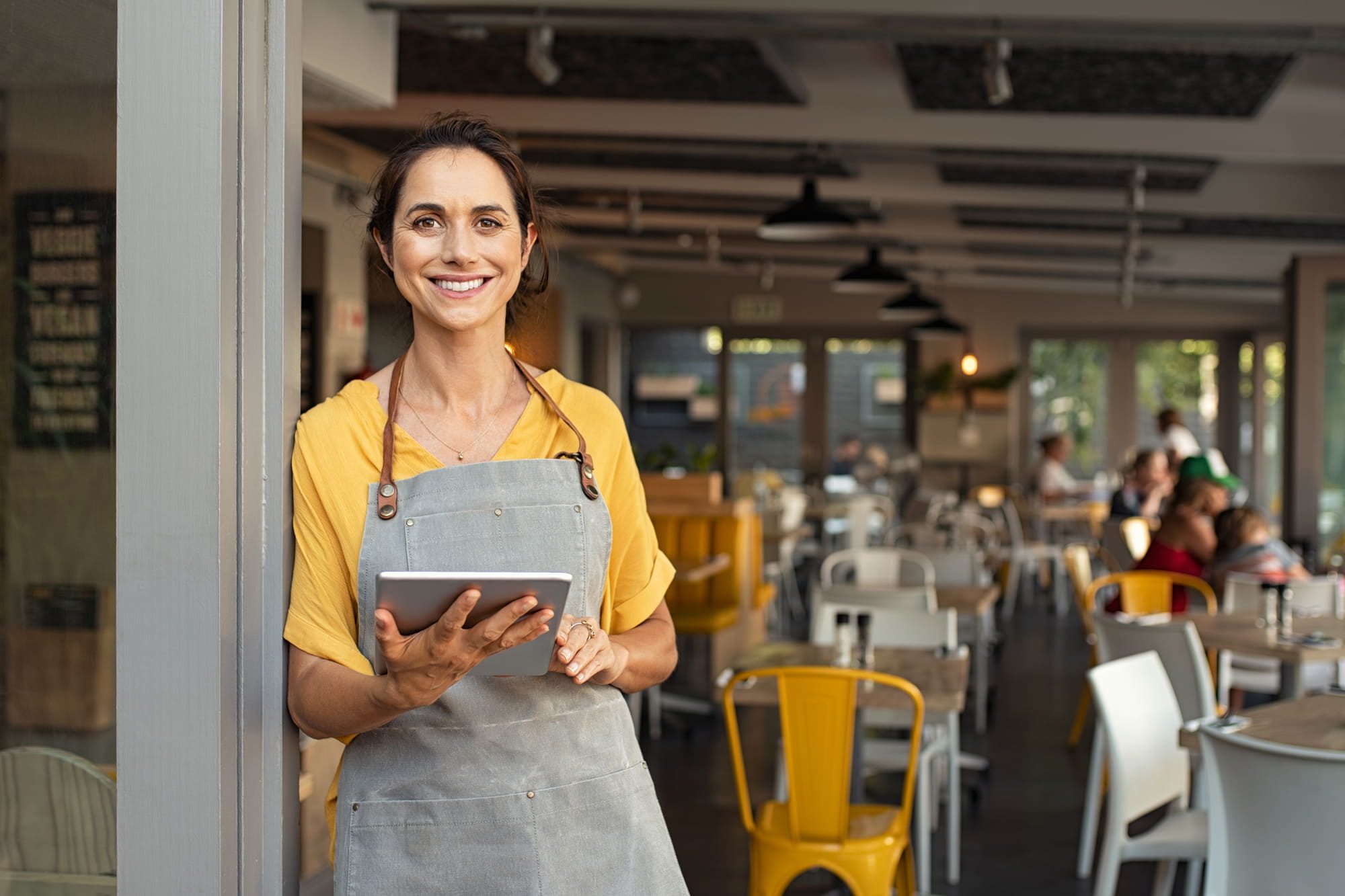 Restauratrice utilisant une tablette pour gérer son restaurant et optimiser le travail des équipes grâce à la digitalisation