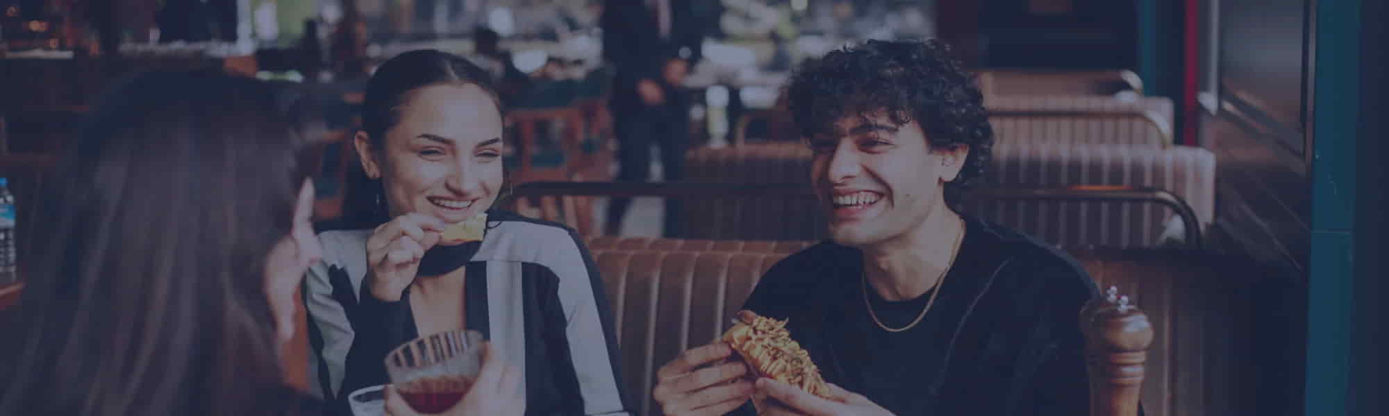 Deux clients souriants partageant un repas dans un restaurant convivial.