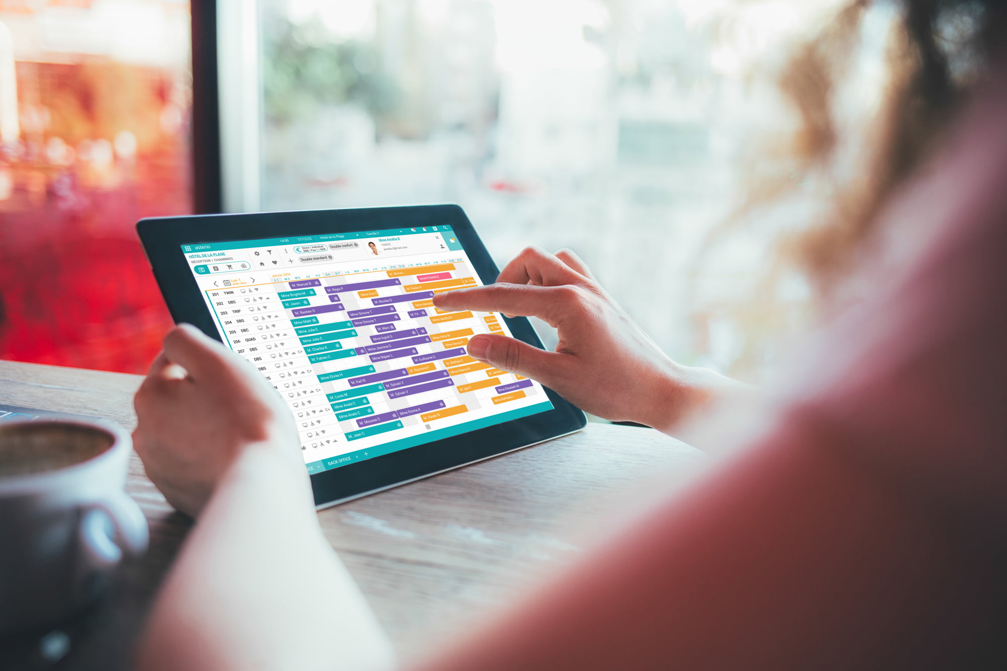 Personne utilisant une tablette pour gérer un planning de réservations hôtelières