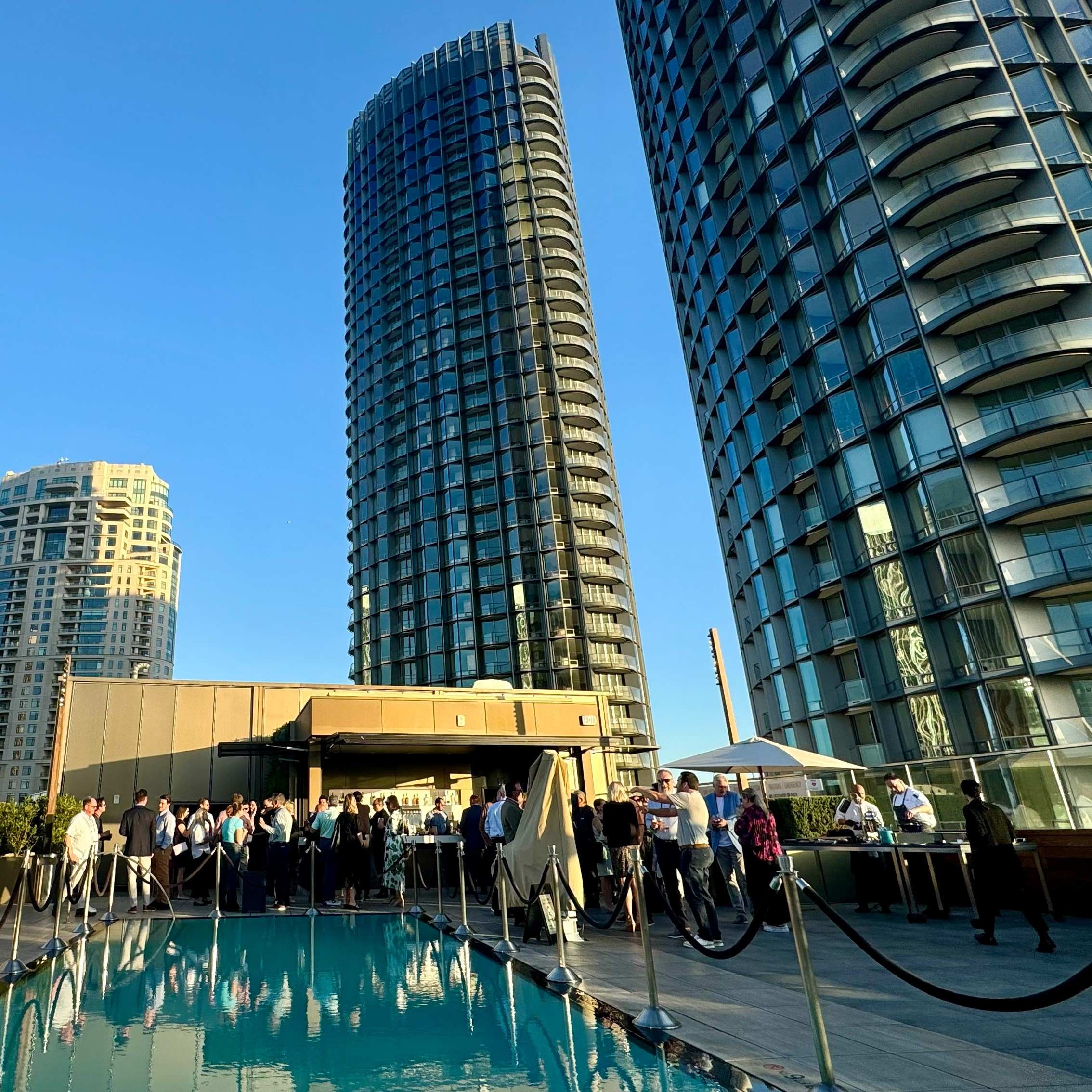Attendees networking beside a rooftop pool among city towers