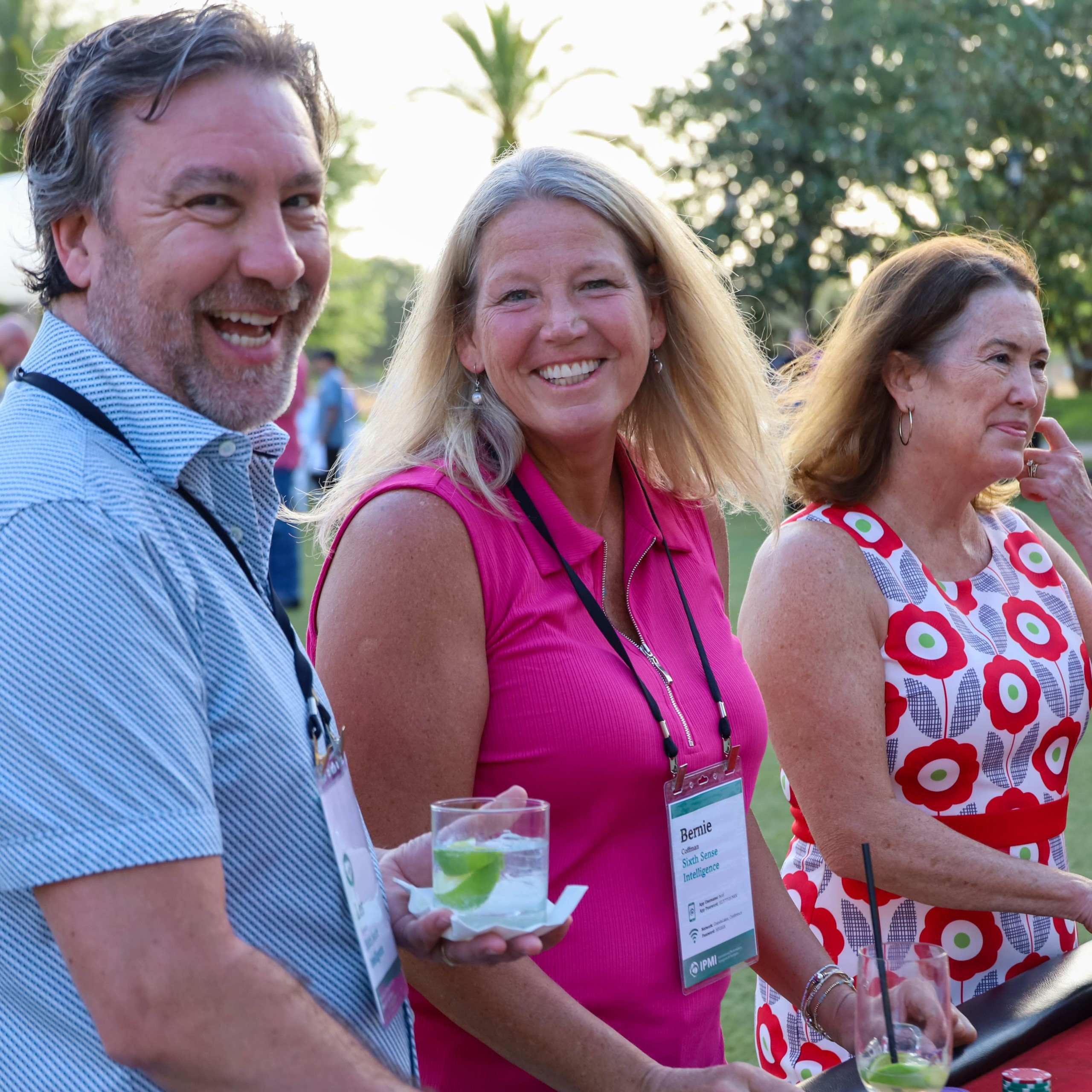 Participants smiling with drinks at an outdoor IPMI gathering