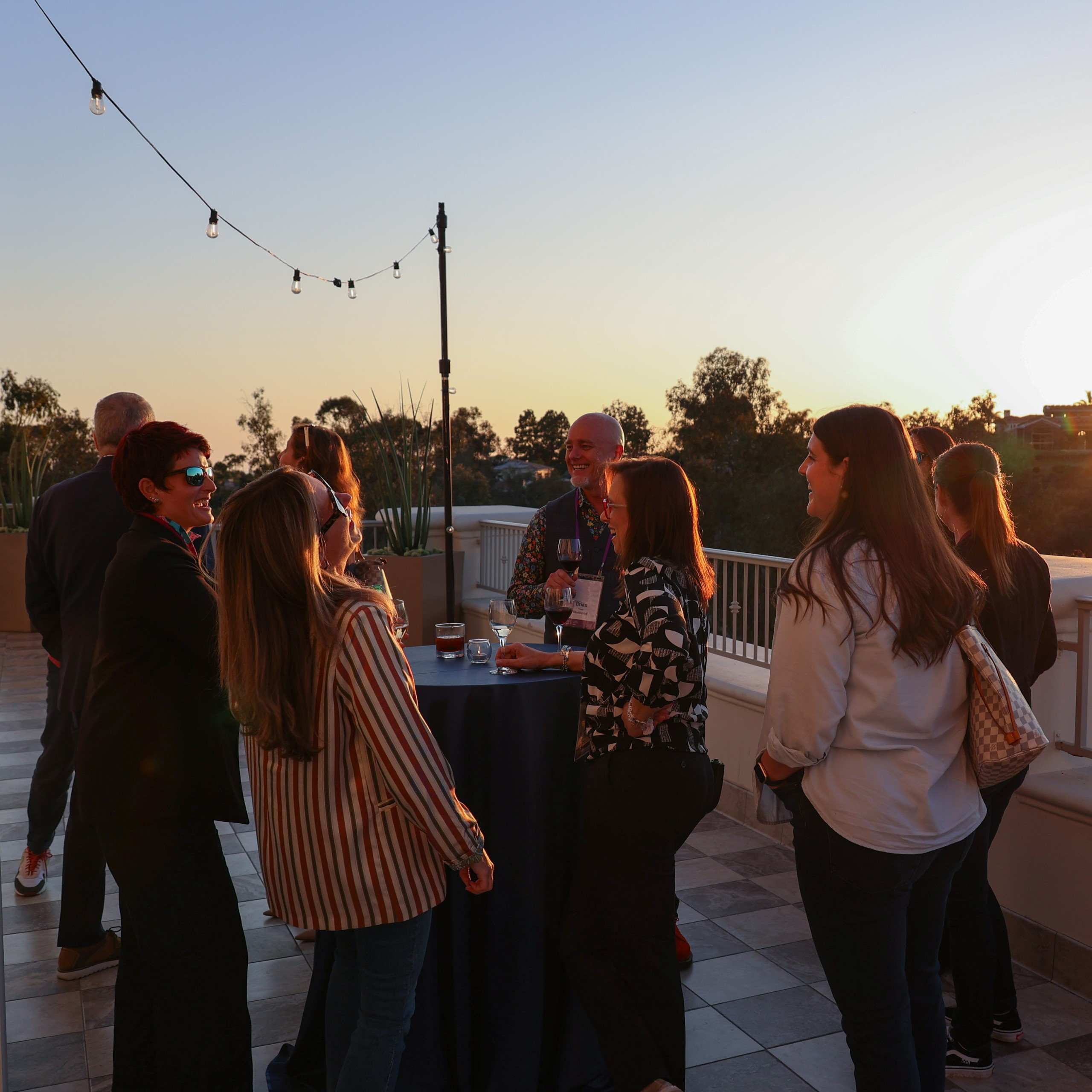 Attendees networking outdoors around a cocktail table at sunset