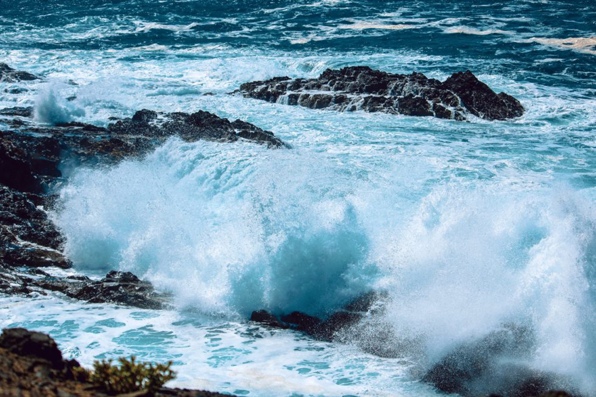 A beach-cliff image with agitated waves clashing agains rocks