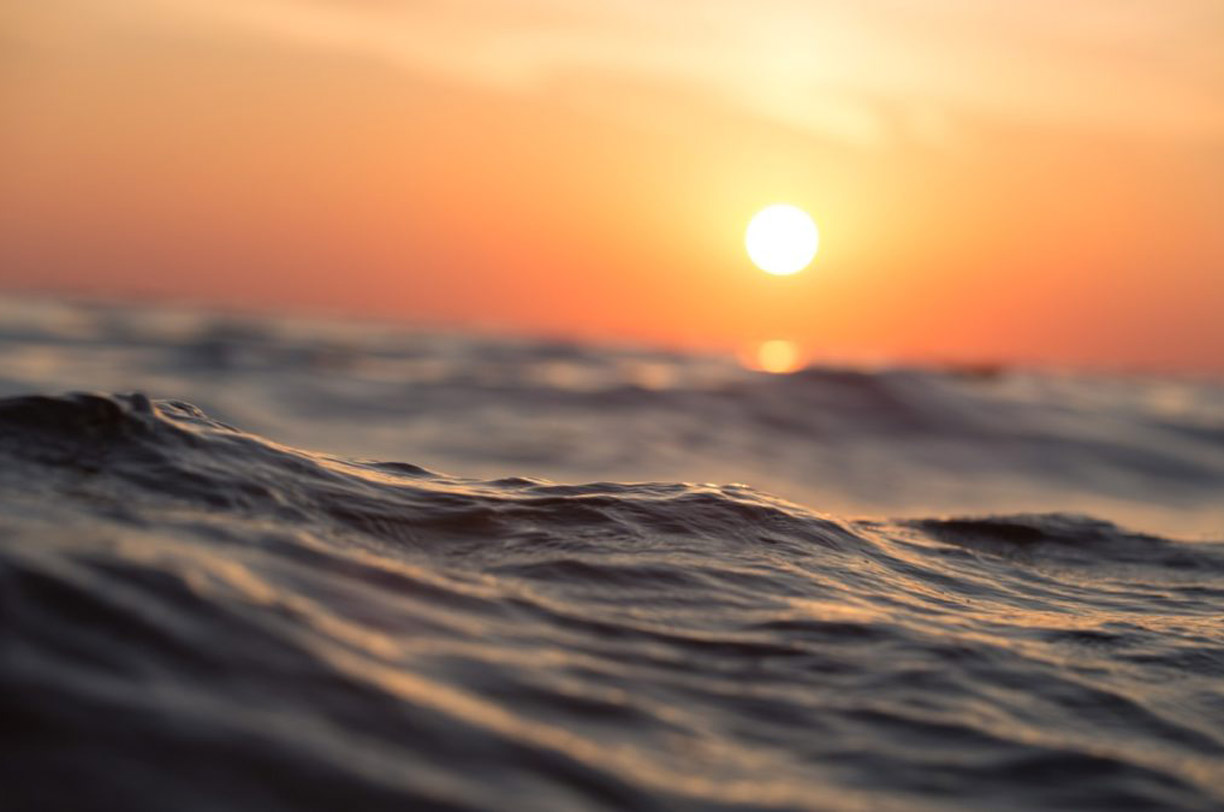 An image of an orange sunset over the sea waves.