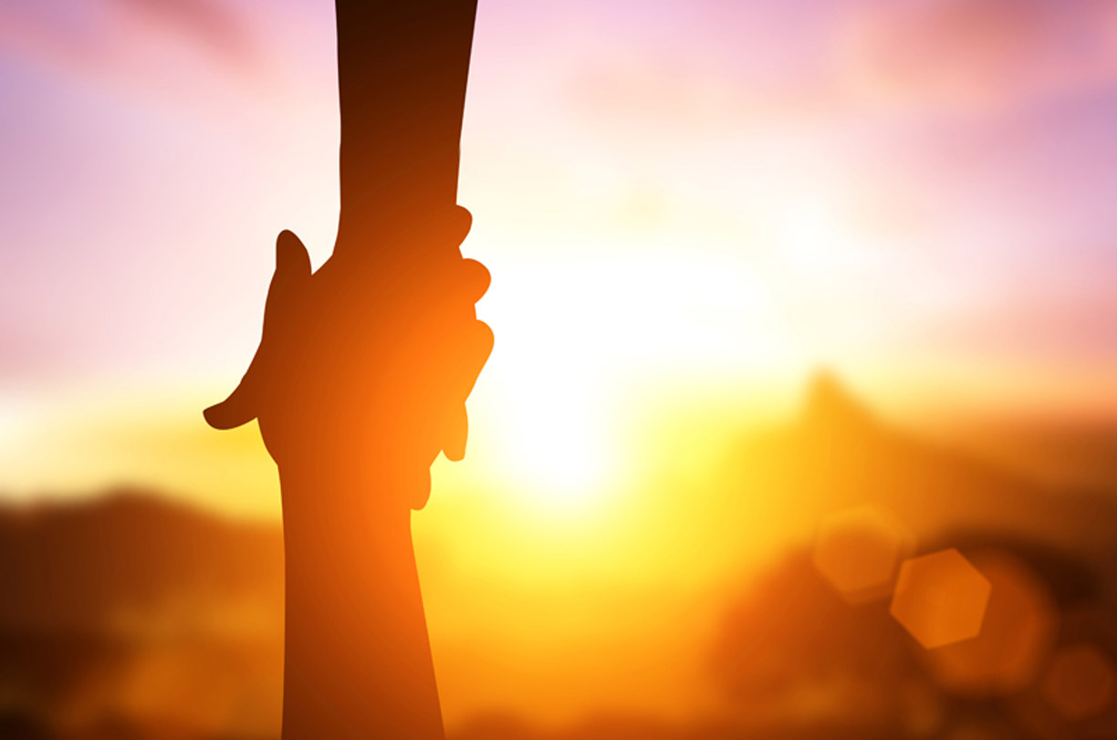 An image of a close up on two hands helping each other.