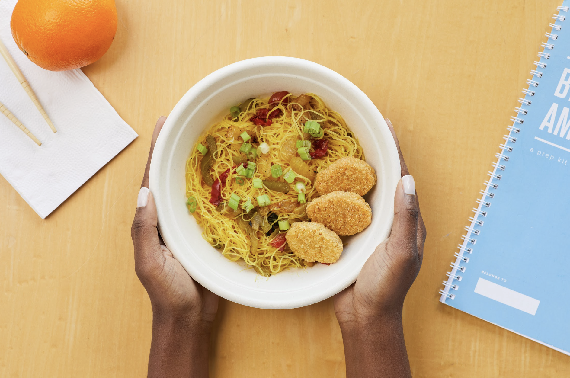 hands holding paper bowl with culturally relevant school lunch