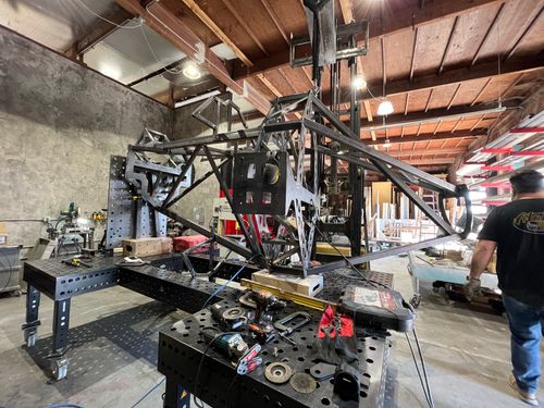 A partially assembled steel armature resting on a welding table.