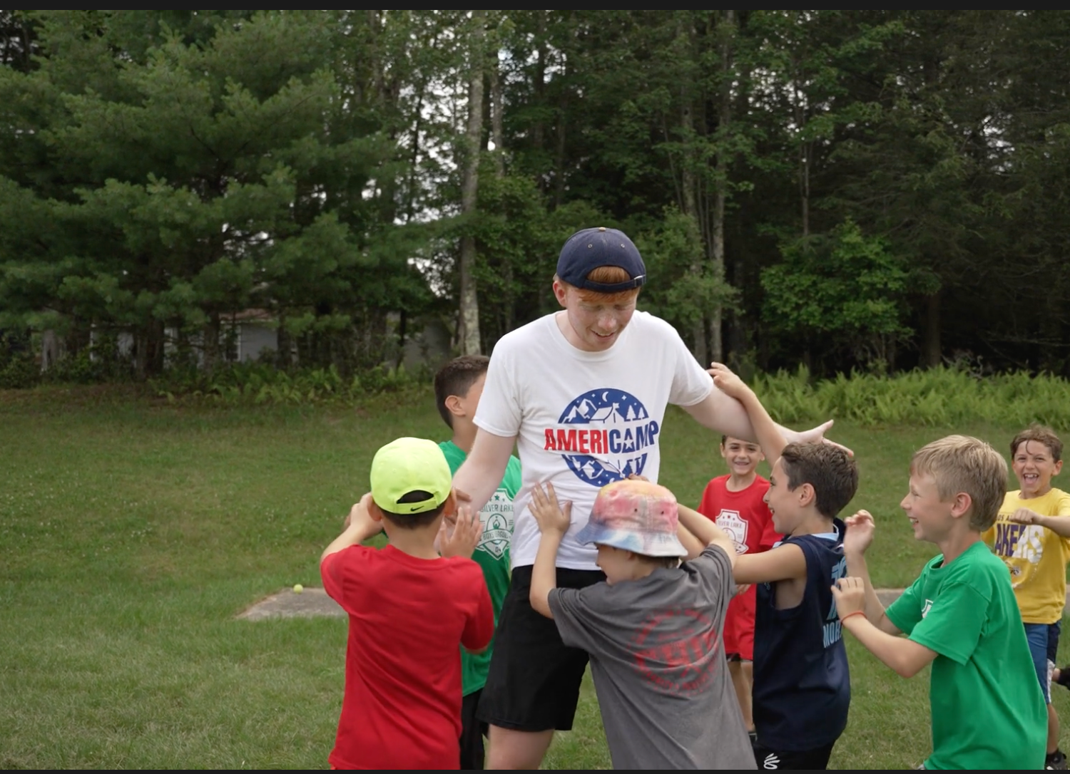 An AmeriCamp counsellor playing with a group of campers on a field