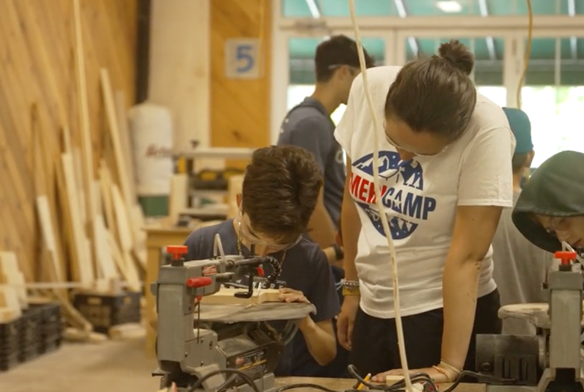 An AmeriCamp camp counsellor and camper doing woodwork activities