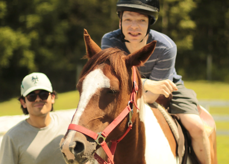 Camper at Camp Anne riding a horse while a camp counsellor supervises