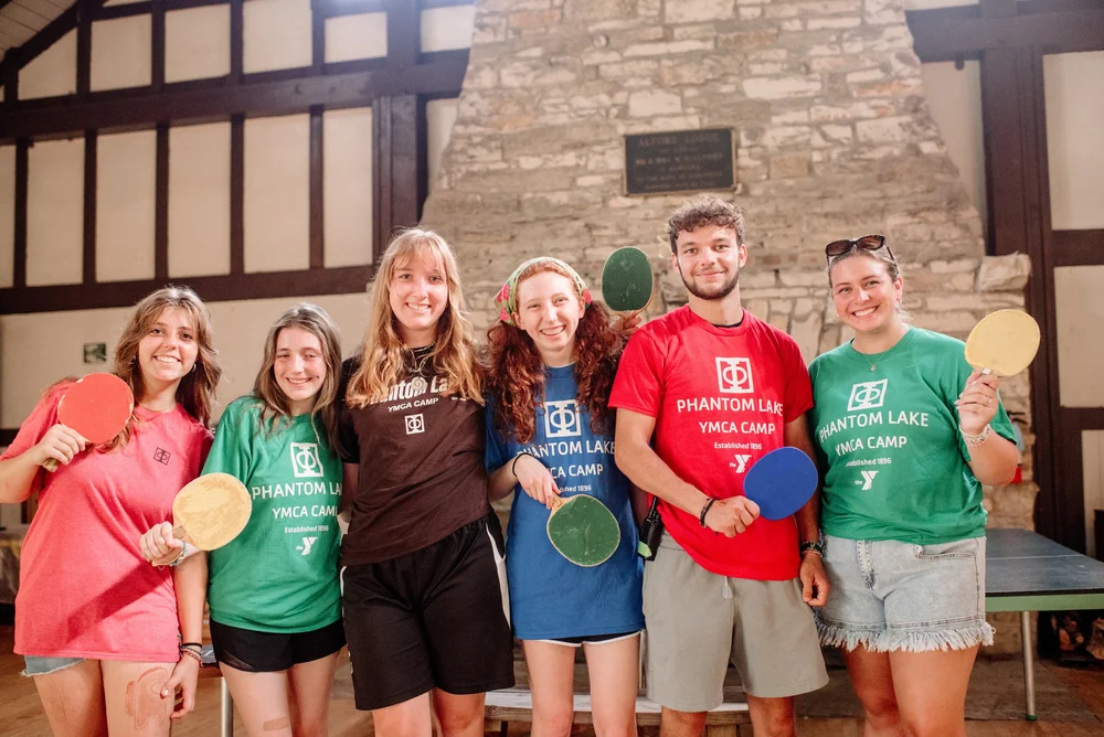Phantom Lake YMCA Camp counsellors and participants holding table tennis paddles