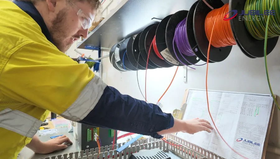 Jubilee Energy technician checking a wiring diagram inside a control panel