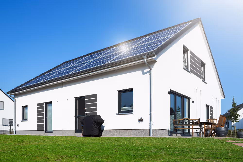 Modernes Einfamilienhaus mit installierter Photovoltaikanlage auf dem Dach bei strahlend blauem Himmel – Symbol für nachhaltige Stromerzeugung und Energiewende.