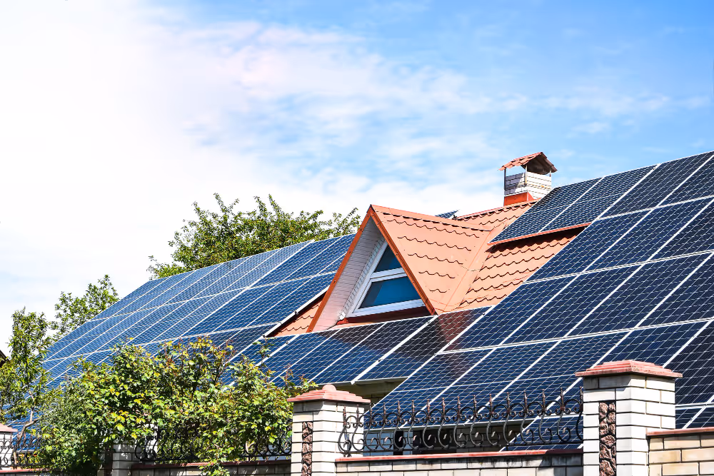 Einfamilienhaus mit rotem Ziegeldach und großflächiger Photovoltaikanlage, aufgenommen bei Sonnenschein – Symbol für nachhaltige Energie und Strom vom eigenen Dach