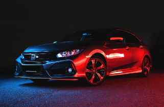side view of a honda with multi-colored lights reflecting off the car