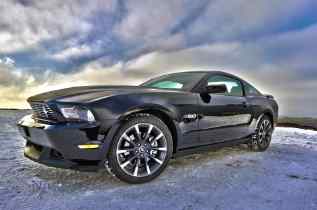 side view of a ford mustang with a cloudy blue sky in the background