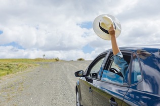 blue car on the road with a persons hand outside the car window