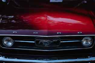 close up of the grill and hood of a red ford mustang
