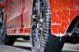 bottom view of a red car with soapy water running down the panels