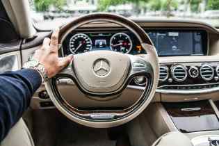 steering wheel with a man's hand holding the steering wheel on the left side
