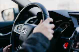 close up of a steering wheel with two hands on the wheel