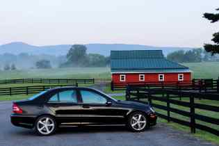 side view of a car parked in front of a wooden fence