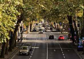 a view from above of a four lane road lined with trees and cars driving in both directions