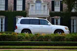 side view of a white toyota suv behind a short hedge