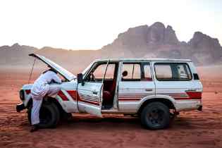 side view of a broken down car with the hood up