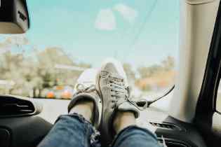 front passenger's feet on the dashboard with the mountains and blue sky in the background