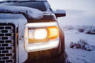 close up of a pick up truck with the headlights on under some snow