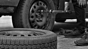 two tires, one on the car and one on its side on the floor