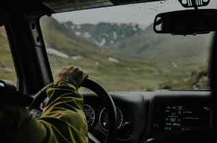 dashboard, windshield, and driver's hand with the view from the back seat of a car
