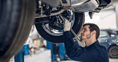 Mechanic inspecting engine under open car hood