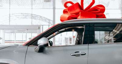A woman is dangling her keys out of her window after buying her new car. 