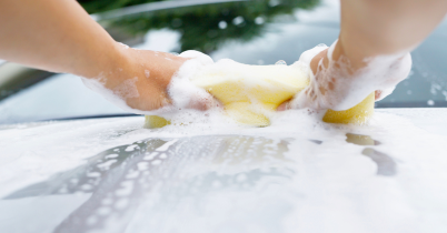 bottom view of a red car with soapy water running down the panels