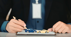 Business professionals shaking hands over a vehicle service contract agreement with car keys and vehicle documents on a desk
