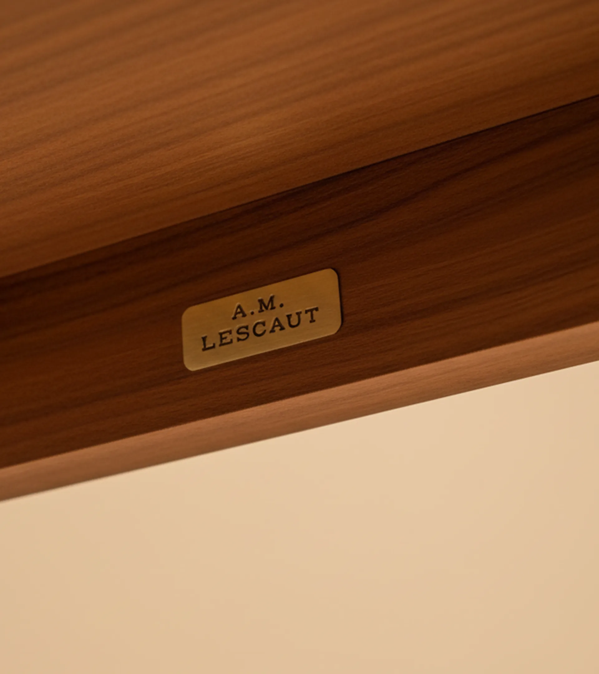 Gros plan d'une table en bois avec une plaque en laiton gravée A.M. LESCAUT.