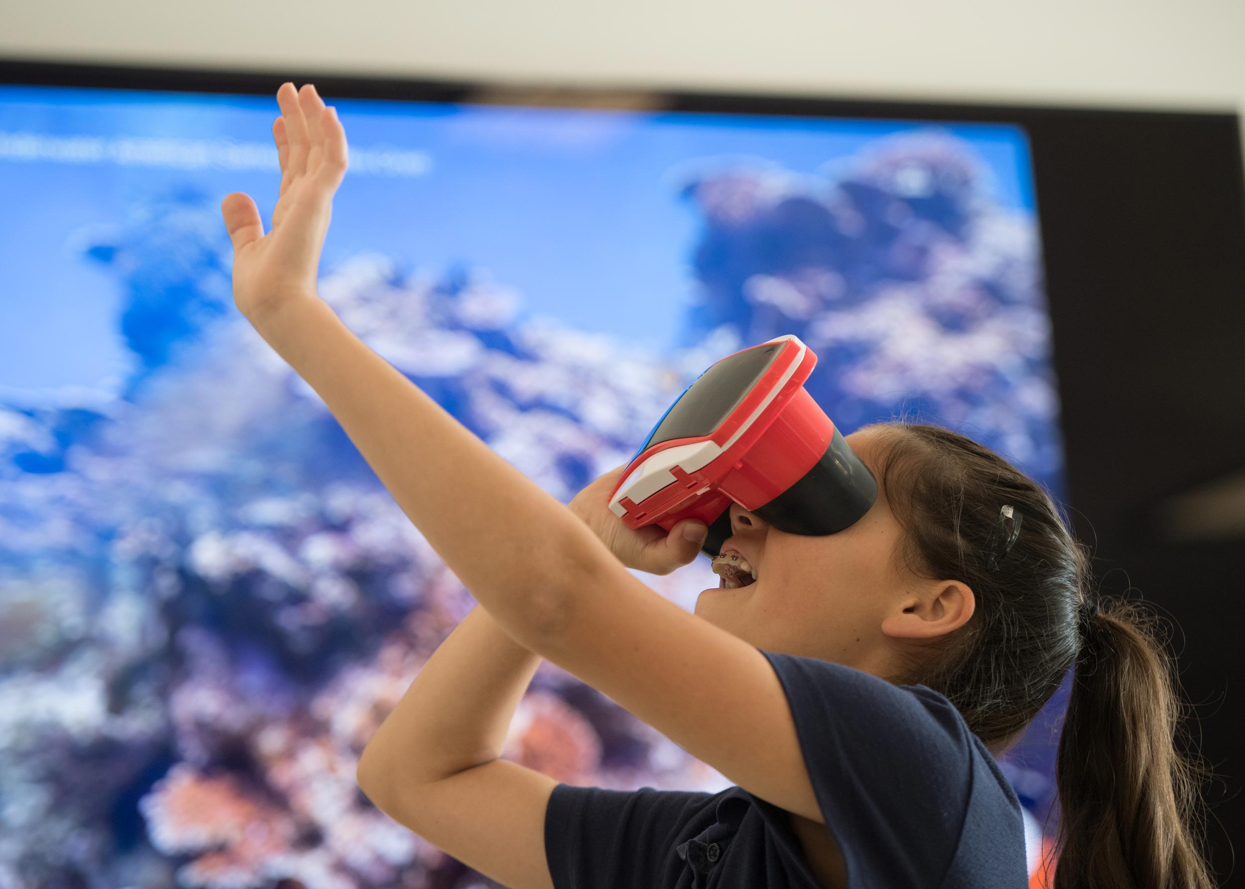 Young girl interacting with virtual reality through VR headset
