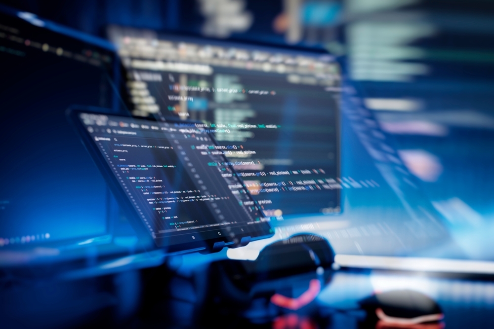 A close-up shot of a monitor and a tablet displaying lines of code, indicating software development or programming.