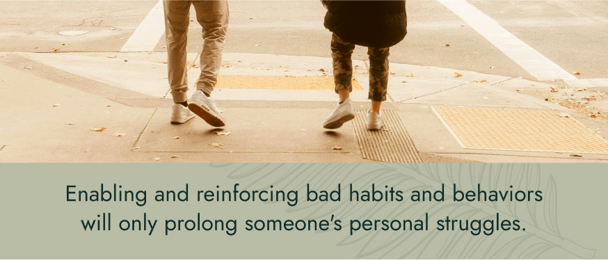 Image: The feet of two people walking next to each other down a city street. Text: Enabling and reinforcing bad habits and behaviors will only prolong someone's personal struggles.