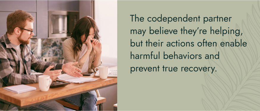 Image: A couple having a heated discussion in the kitchen with papers, calculators, and a computer on the table. Text: The codependent partner may believe they're helping, but their actions often enable harmful behaviors and prevent true recovery.