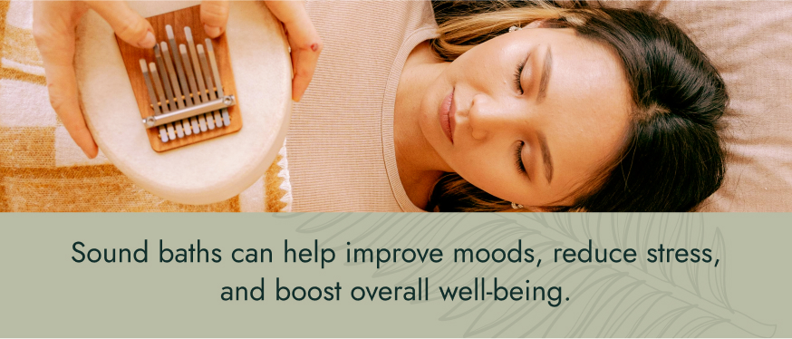 Image: A woman taking a soundbath, lying down with her eyes close, while the soundbath guide play an instrument above her. Text: Sound baths can help improve moods, reduce stress, and boost overall well-being