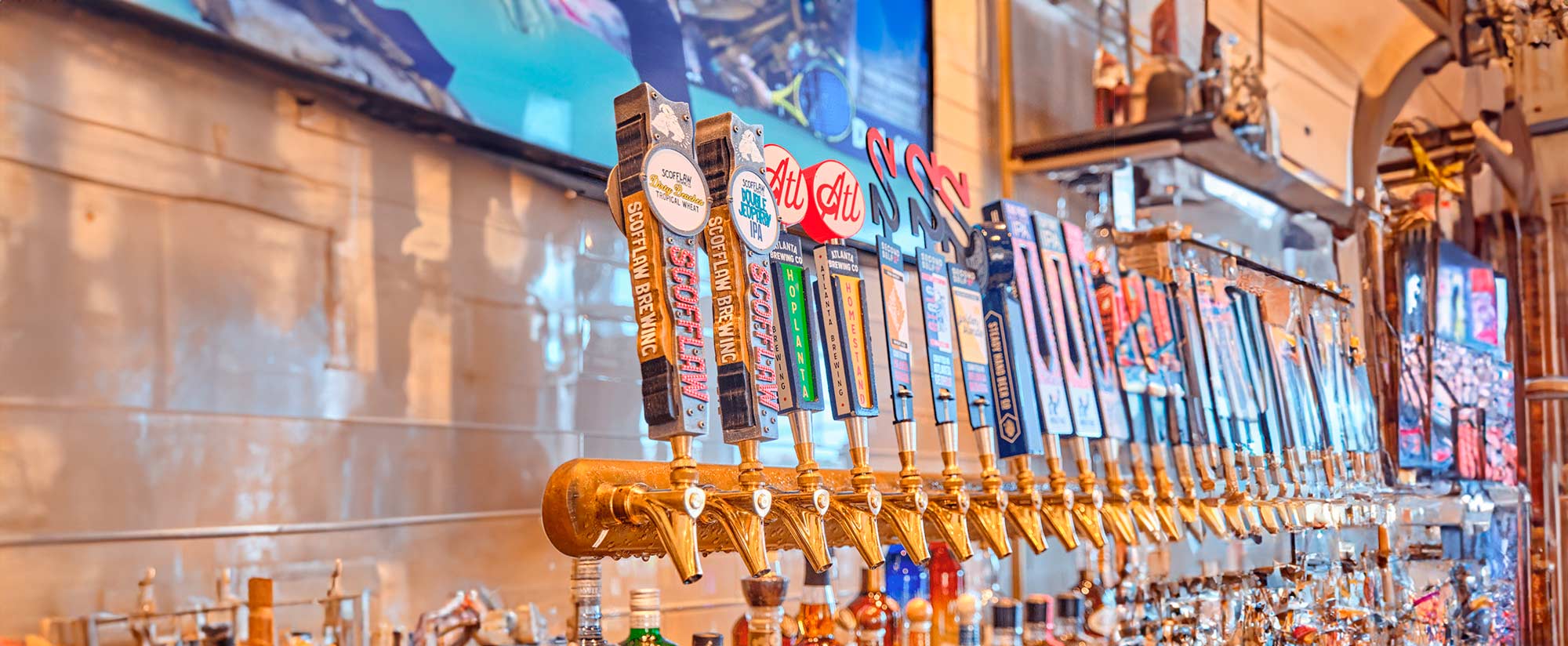 Close-up of multiple colorful beer taps in a row at a bar.
