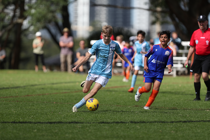 Youth boy kicking soccer ball.