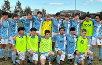 Youth soccer team posing together on grass field with some players wearing yellow pinnies.