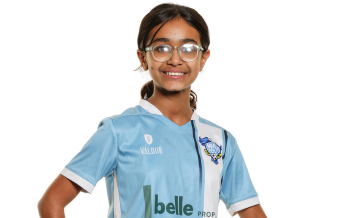 Youth soccer team posing together on grass field with some players wearing yellow pinnies.