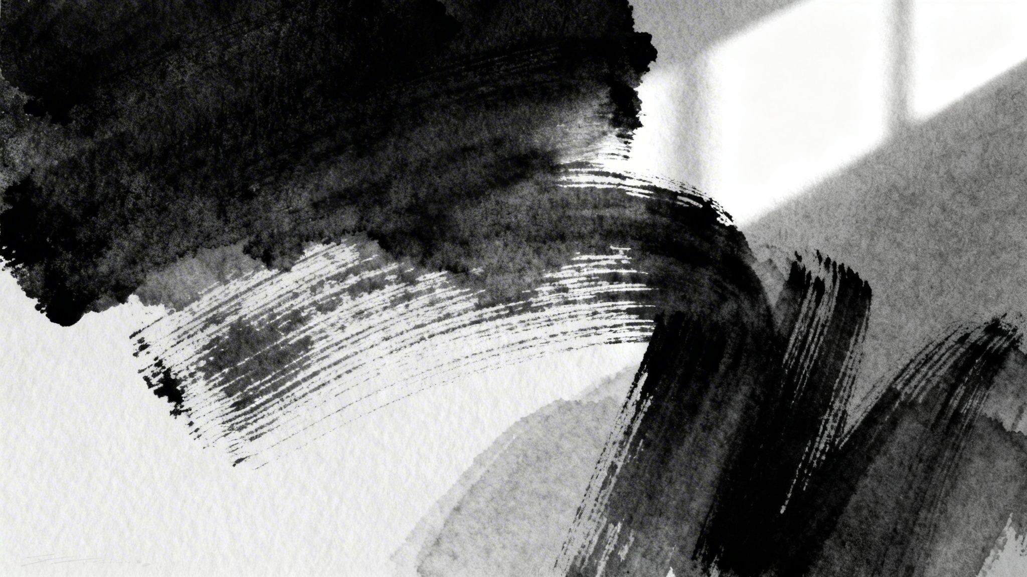 Abstract black ink brushstrokes on textured white paper with a subtle light shadow.