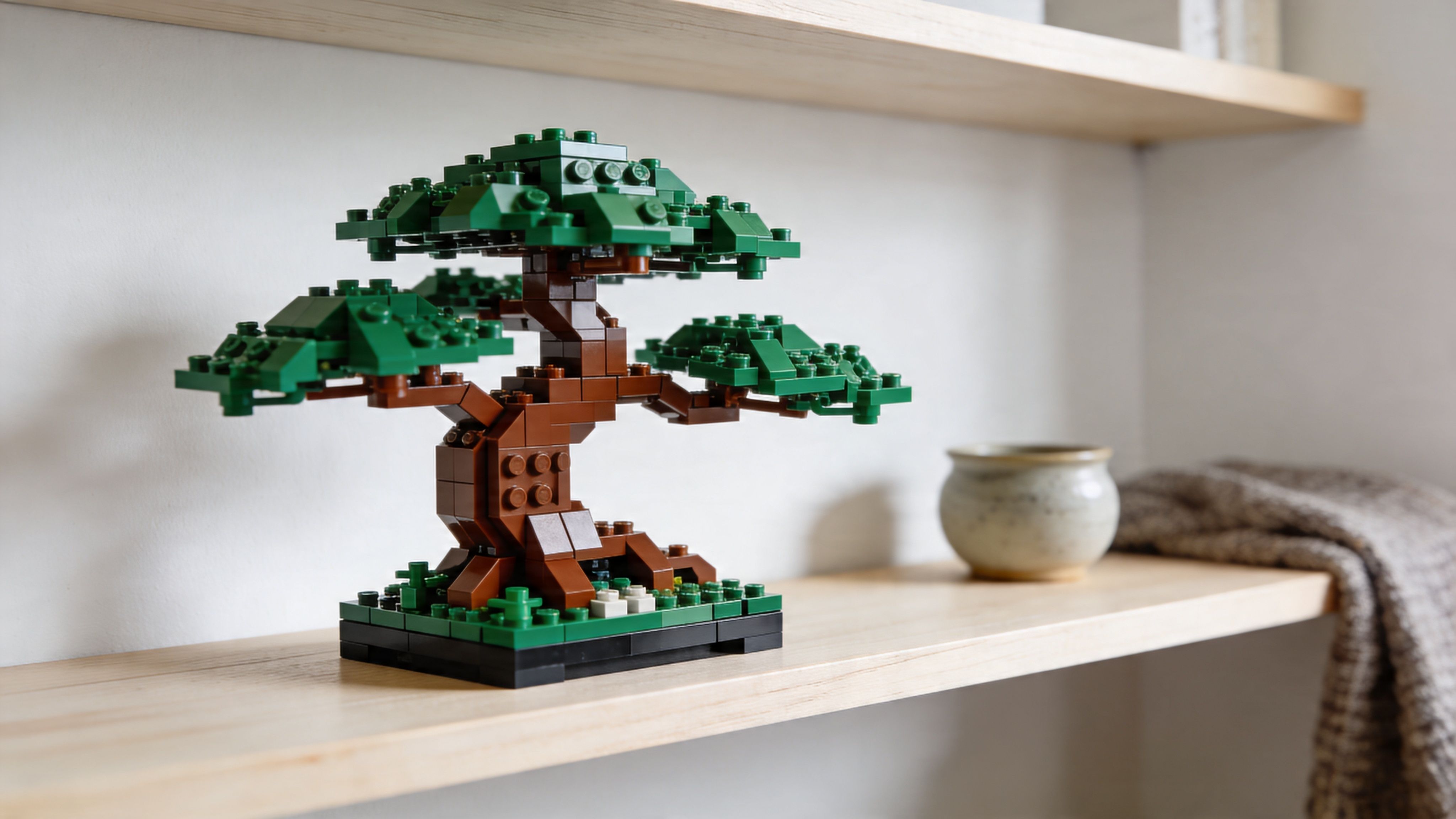 A detailed LEGO bonsai tree model displayed on a wooden shelf in a minimalist room setting.