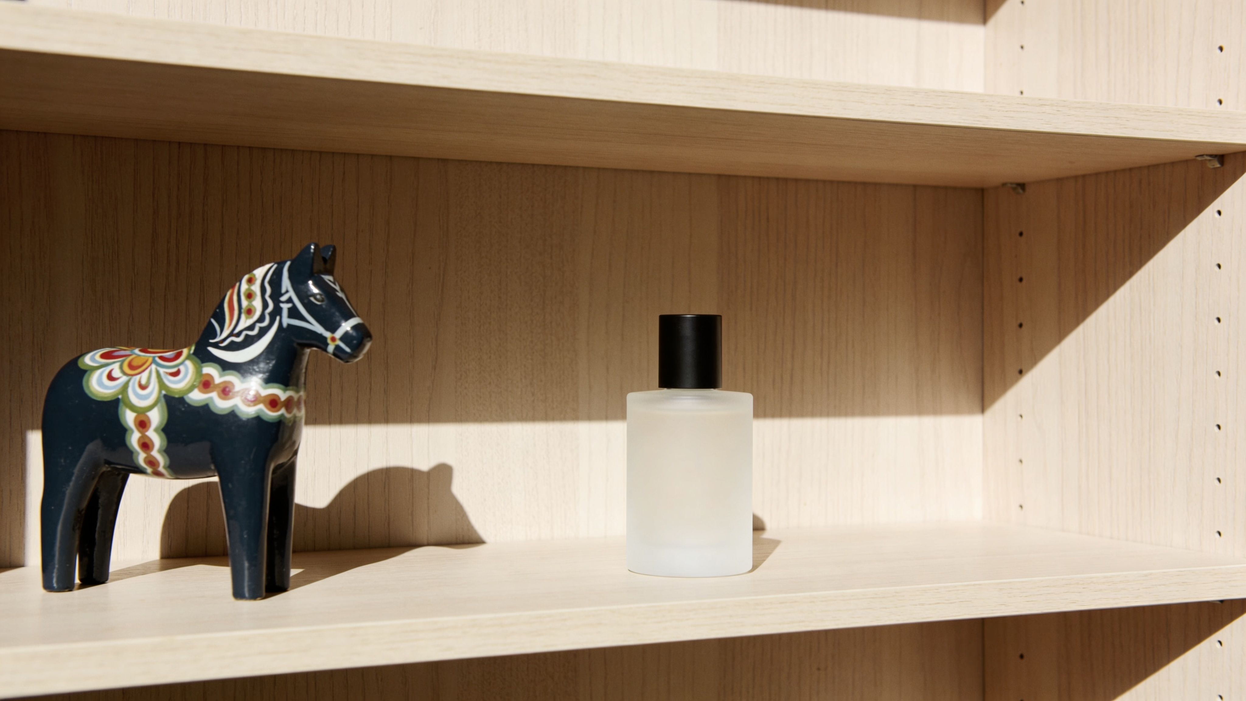 A minimalist wooden shelf displaying a traditional blue Dala horse figurine next to a glass perfume bottle.